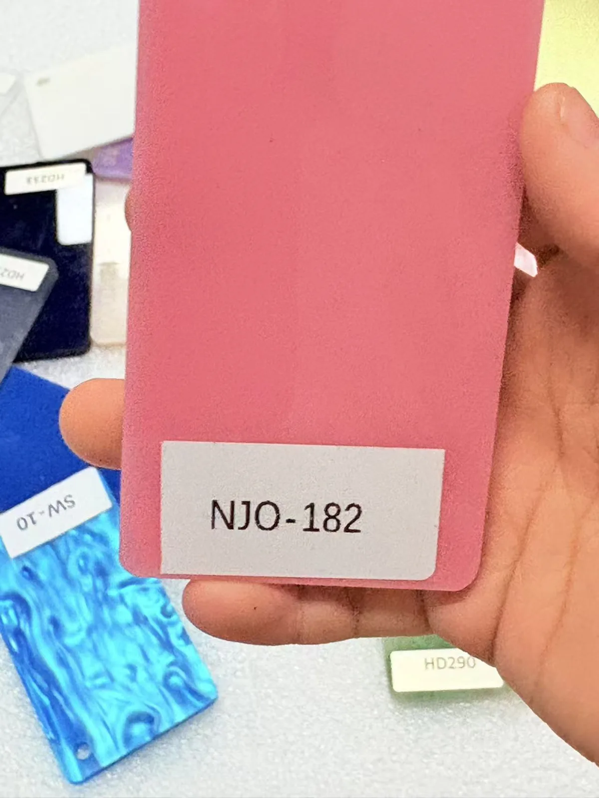 Coral pink acrylic swatch held in hand