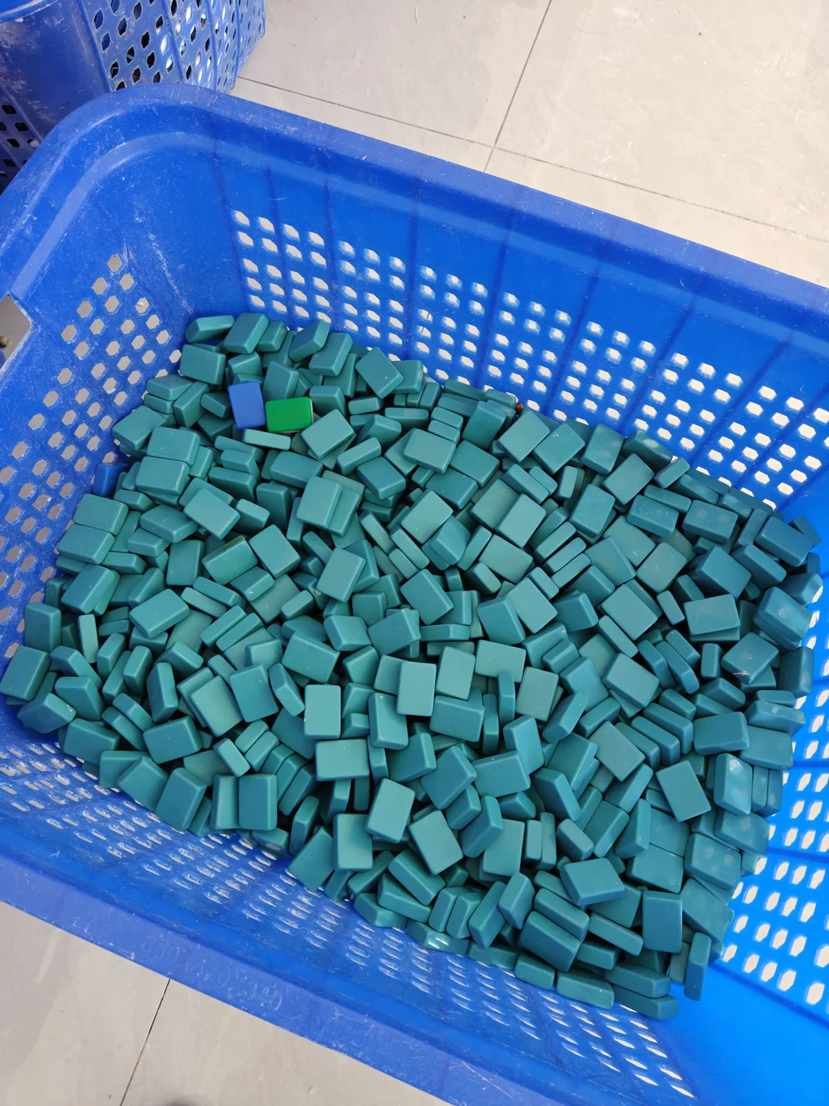 Teal acrylic Mahjong tile blanks in a production basket