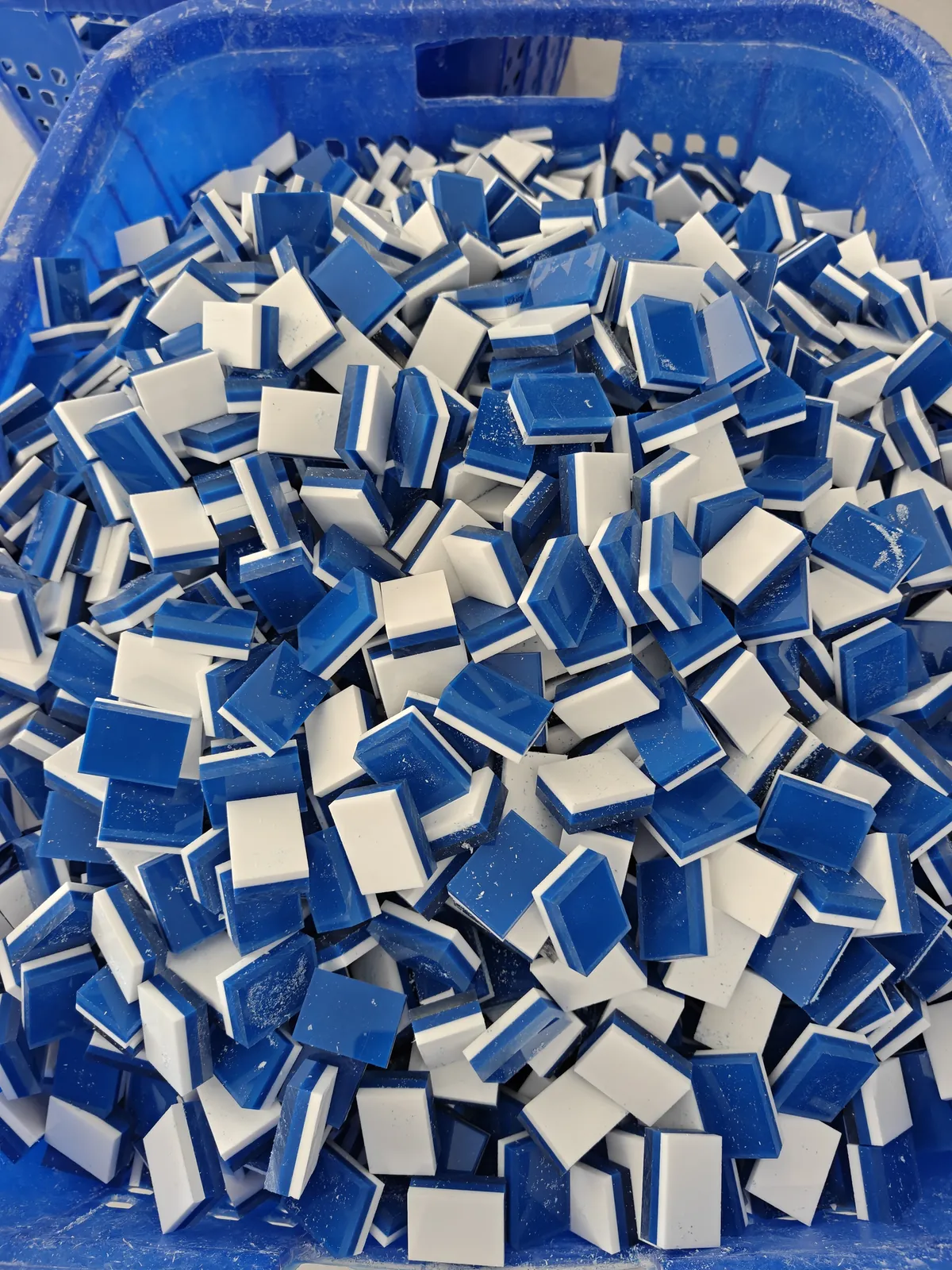 Blue and white layered acrylic Mahjong tile blanks in a production basket