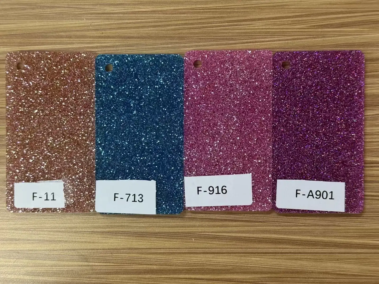 Four stock glitter acrylic color samples labeled with material codes